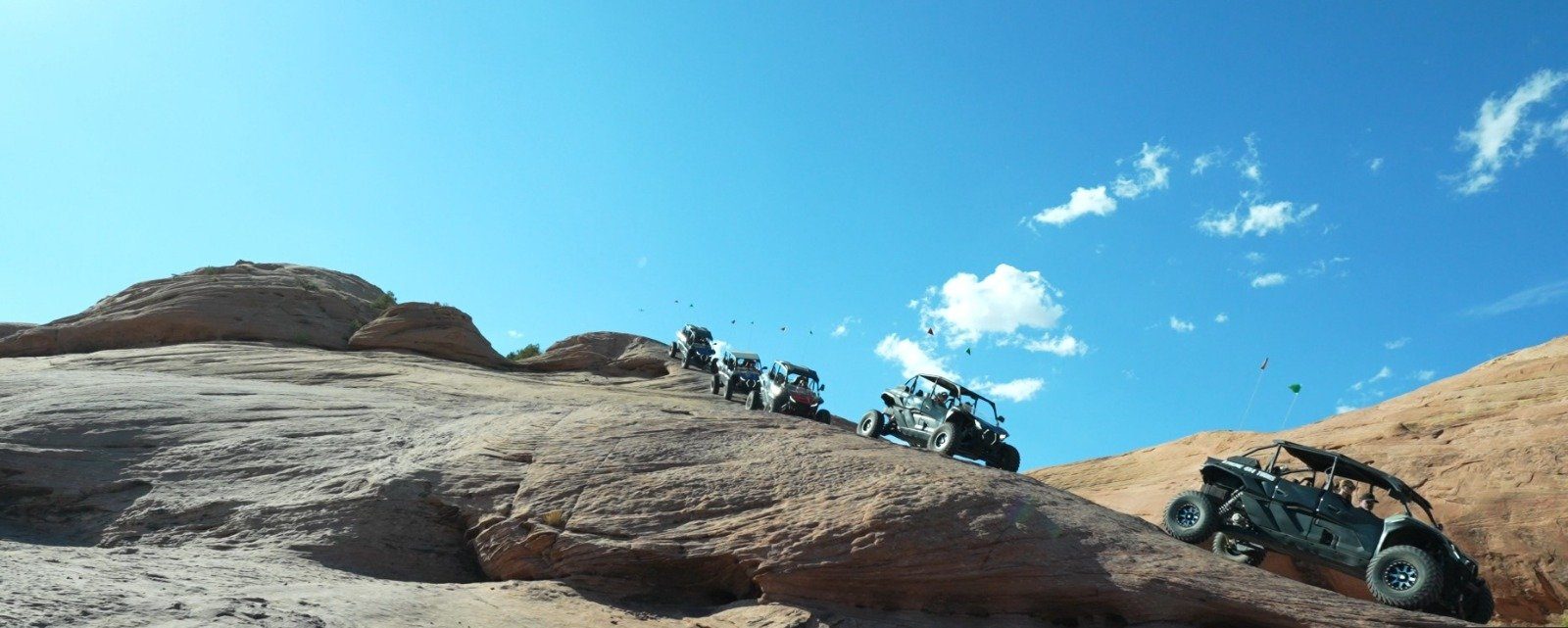 Vehicles climbing a steep slickrock fin on Hell's Revenge